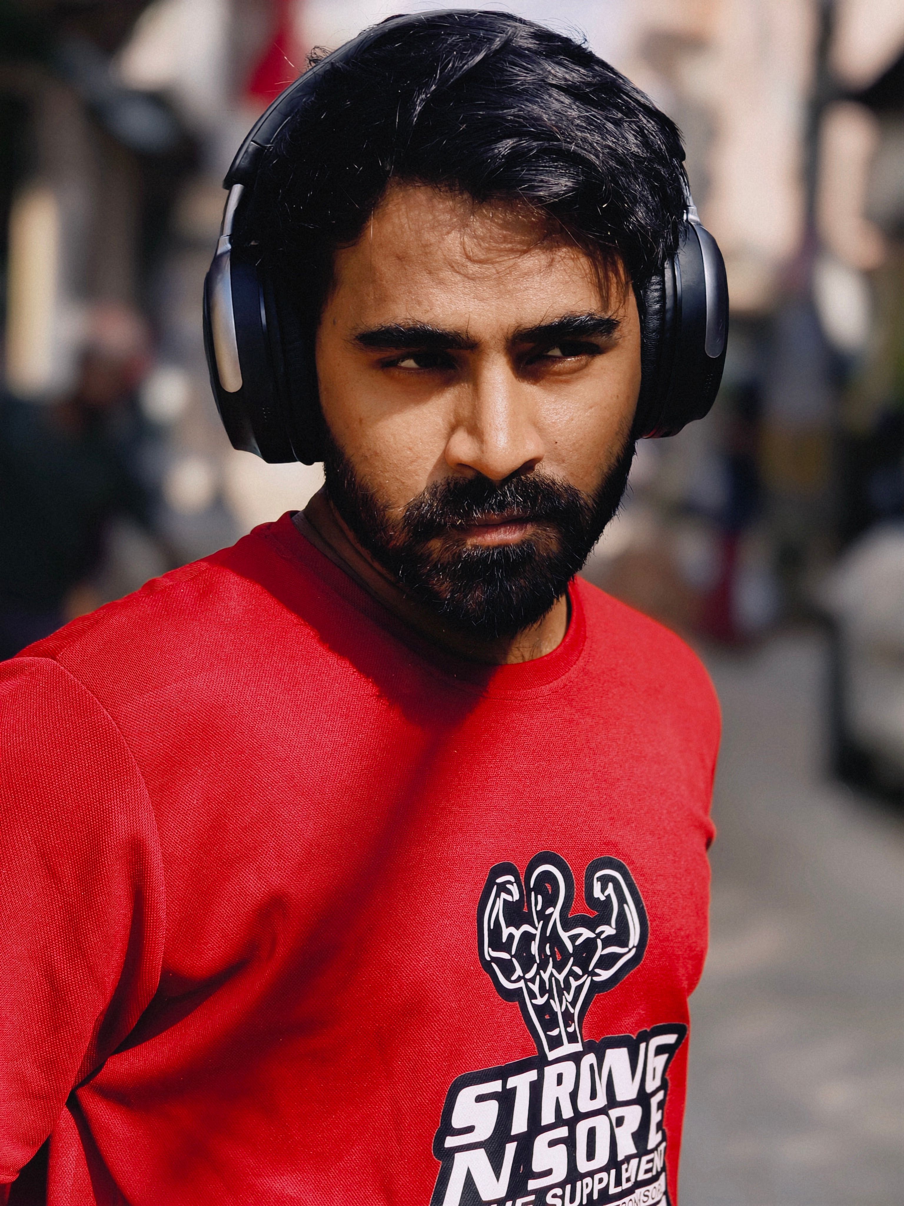 Portrait of a focused male athlete with headphones in a casual urban setting.