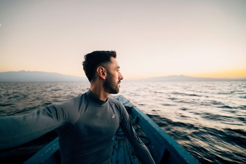 Free A man in a boat enjoying a peaceful sunset on the sea, looking towards the horizon. Stock Photo