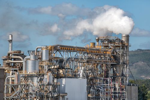Free A large industrial factory emits smoke into the sky, showcasing industrial activity and pollution. Stock Photo