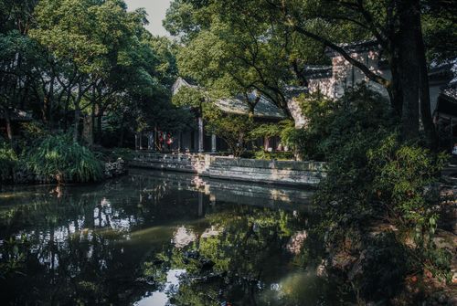 Free Serene view of a traditional Chinese garden with lush greenery and a peaceful pond. Stock Photo
