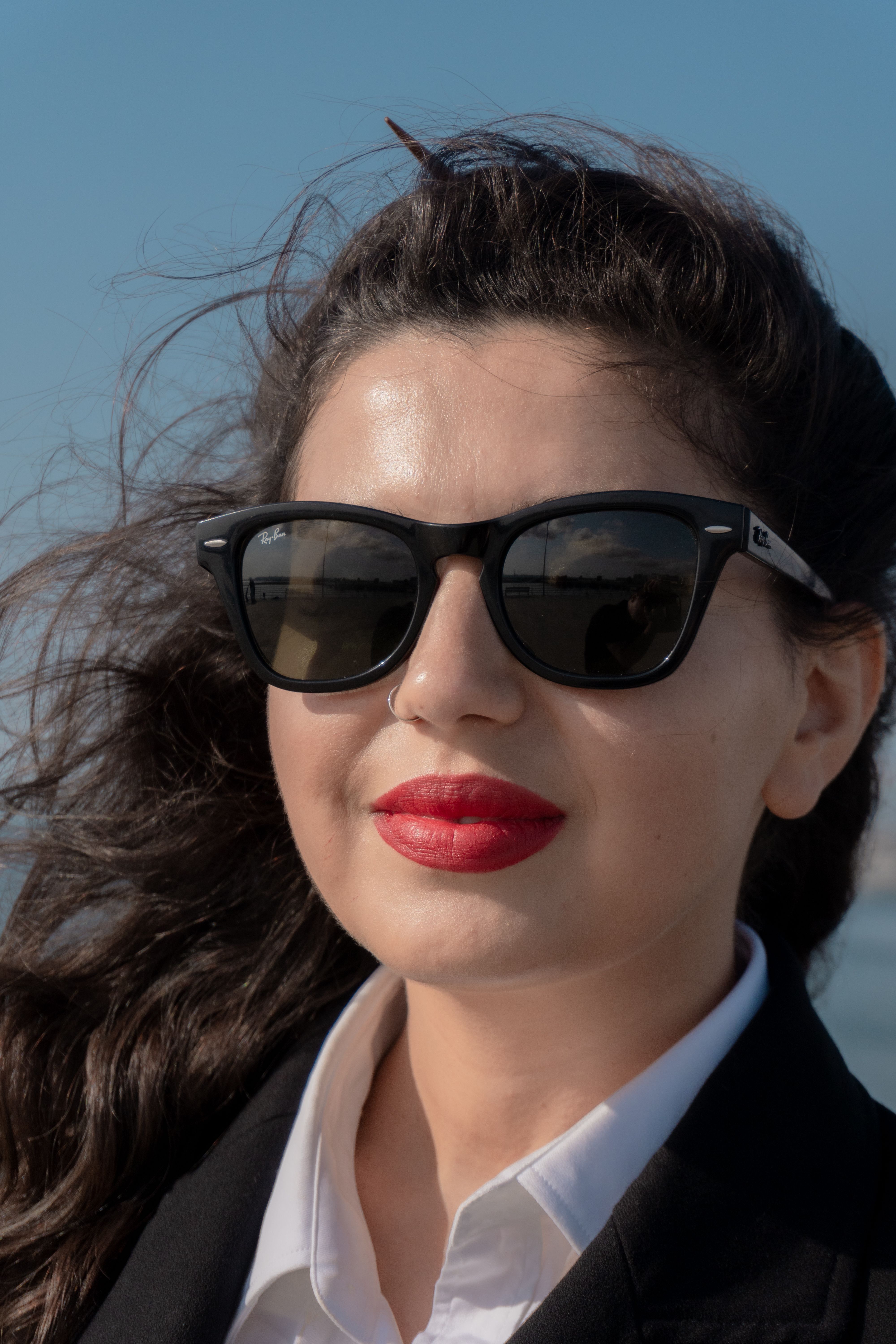 Close-up of a stylish woman wearing sunglasses and red lipstick outdoors in Baku.