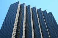 低角度视角下的现代摩天大楼，反光玻璃立面映衬着清澈的蓝天