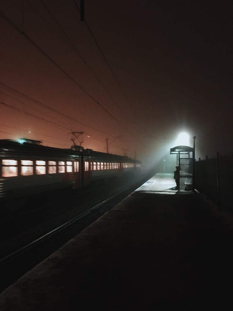 Silhouette Of Person Standing On Train Platform At Night Time