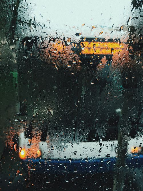 Free Moody scene of raindrops on a window with blurred city lights in the background. Stock Photo