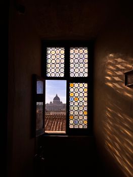 A view of St. Peter's Basilica in Rome through a patterned window, enhancing the historic charm.