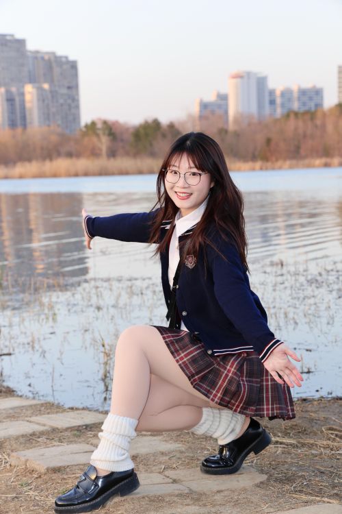 Free A cheerful young woman posing by a lakeside in Hefei, China with modern buildings in the background. Stock Photo