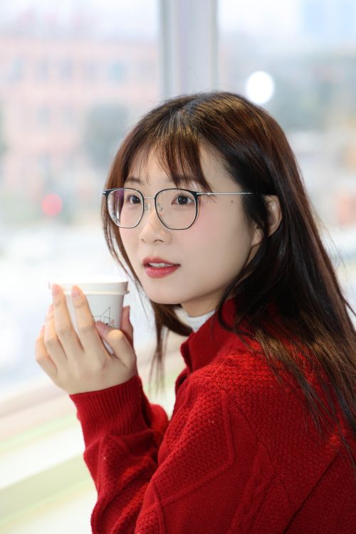 Free Young woman in red sweater enjoys coffee by a window in Hefei, China. Stock Photo