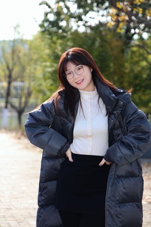 Free A young woman in a winter coat smiles warmly, standing outdoors in Hefei, China. Stock Photo