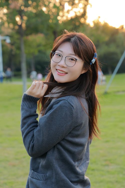 Free A cheerful young woman with glasses enjoys a sunny afternoon in Hefei park. Stock Photo