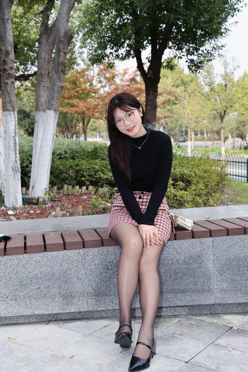Free A fashionable young woman sitting on a bench in a Hefei park during autumn. Stock Photo