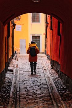 A person walking down a colorful alley in a historic European city, showcasing urban exploration.