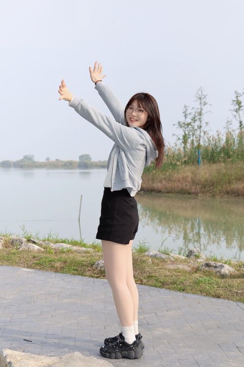 Free Cheerful young woman in casual attire enjoys a peaceful day outdoors by a lake in Hefei, Anhui. Stock Photo