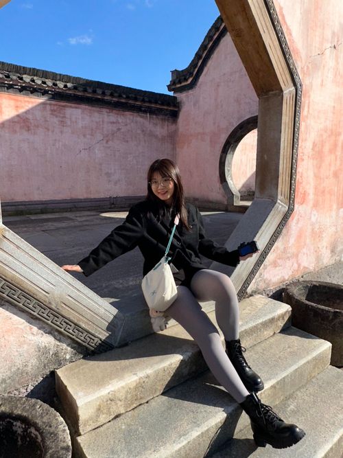 Free Young woman sits on stone steps surrounded by traditional Chinese architecture in Hefei, Anhui, China. Stock Photo
