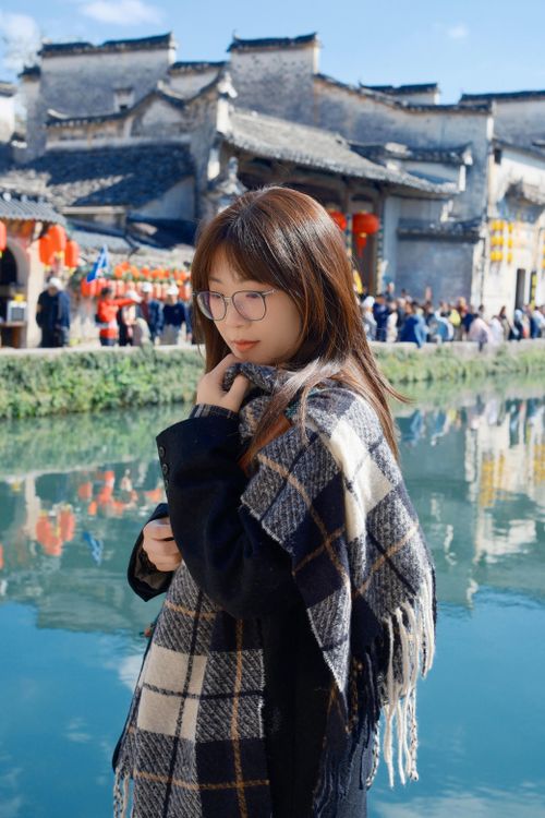 Free A young woman wrapped in a plaid scarf stands by a tranquil canal in Hefei, Anhui, China. Stock Photo