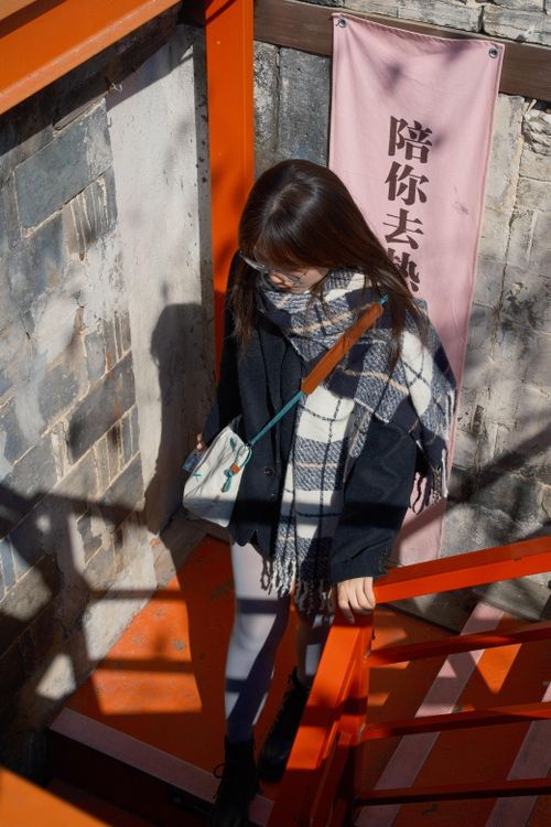 Free An adult East Asian woman descends a bright red staircase with a checkered scarf in Hefei, China. Stock Photo