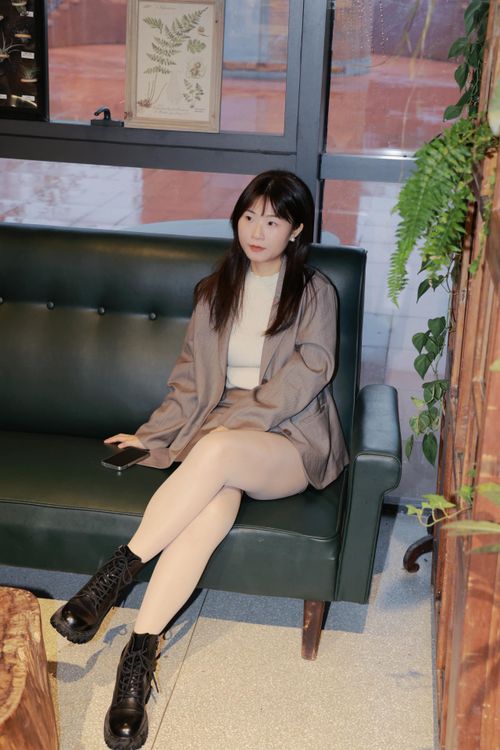 Free Woman sitting on a green couch indoors, surrounded by plants, in Hefei, China. Stock Photo