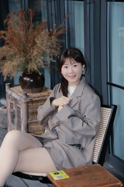 Free Asian woman seated in a gray blazer, enjoying a tranquil moment outside a cafe in Hefei, China. Stock Photo