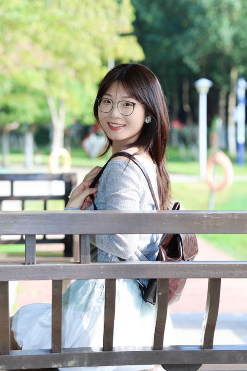 Free Casually dressed young woman with glasses sits on a park bench in Hefei, China. Stock Photo