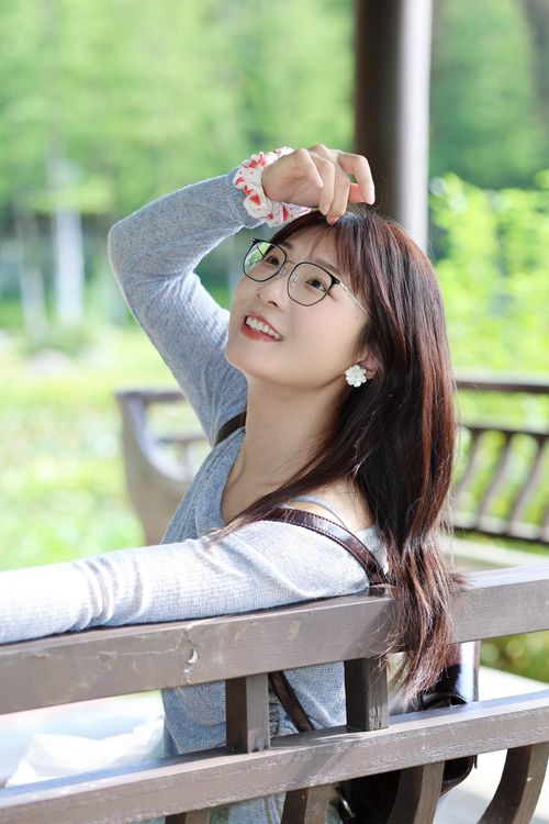Free Smiling young woman with glasses enjoying a sunny day in a Hefei park. Stock Photo