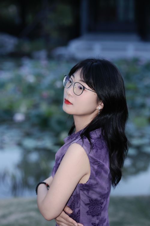 Free Elegant woman in purple standing by a serene lotus pond in Hefei, China, during day. Stock Photo