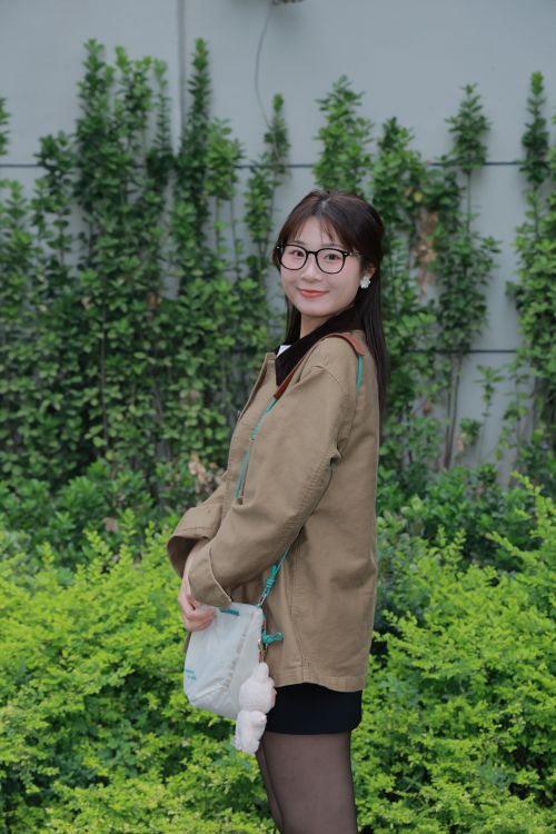Free East Asian woman standing with greenery backdrop in Hefei, China. Stock Photo