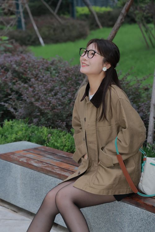 Free Smiling young woman seated on a park bench in Hefei, enjoying an outdoor moment. Stock Photo