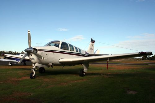 Free Parked light aircraft with propeller on grassy airfield under clear sky. Stock Photo