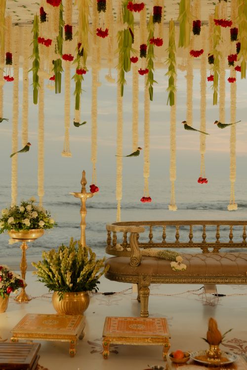 Free Luxurious beachfront wedding setup with ornate seating and floral decor at sunset. Stock Photo