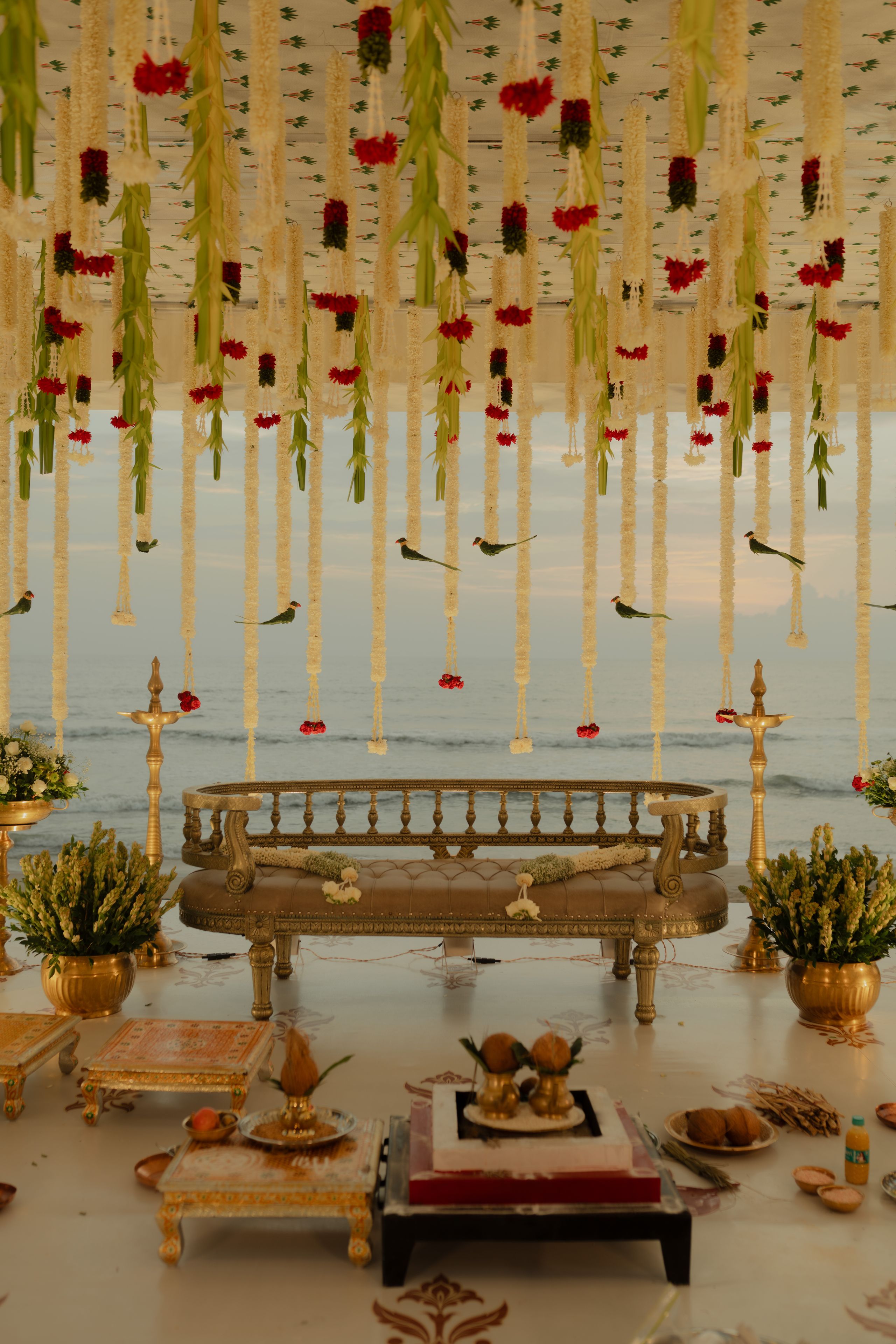 Open-air mandap hung with strands of fresh flowers and set with carved wooden seating
