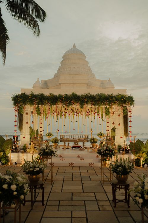 Free Beautifully decorated Indian wedding ceremony setup by the sea with floral arrangements and traditional elements. Stock Photo