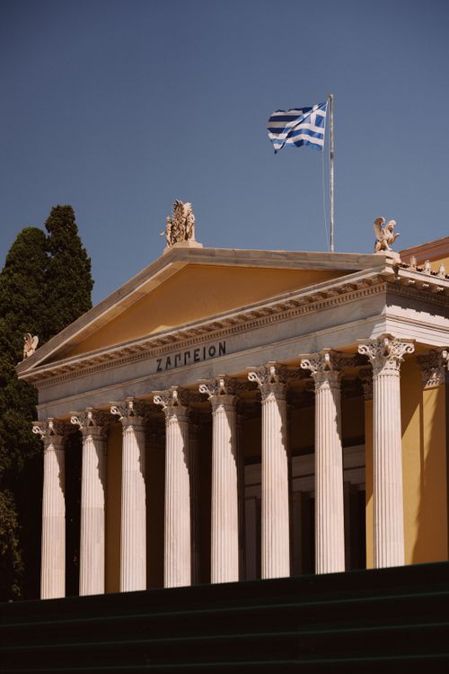Free Zappeion Hall in Athens, Greece, captured with the Greek flag under a clear blue sky. Stock Photo