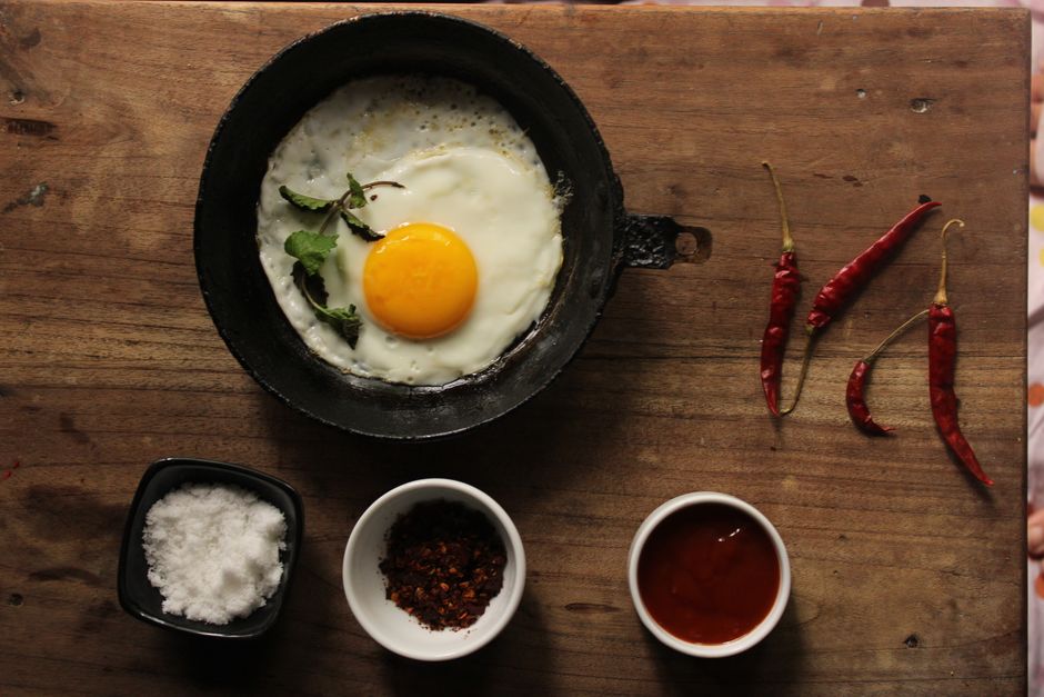 Photo by Jahra Tasfia Reza on Pexels A fried egg in a skillet with spices and red chili peppers on a wooden table. - Photo by Jahra Tasfia Reza on Pexels