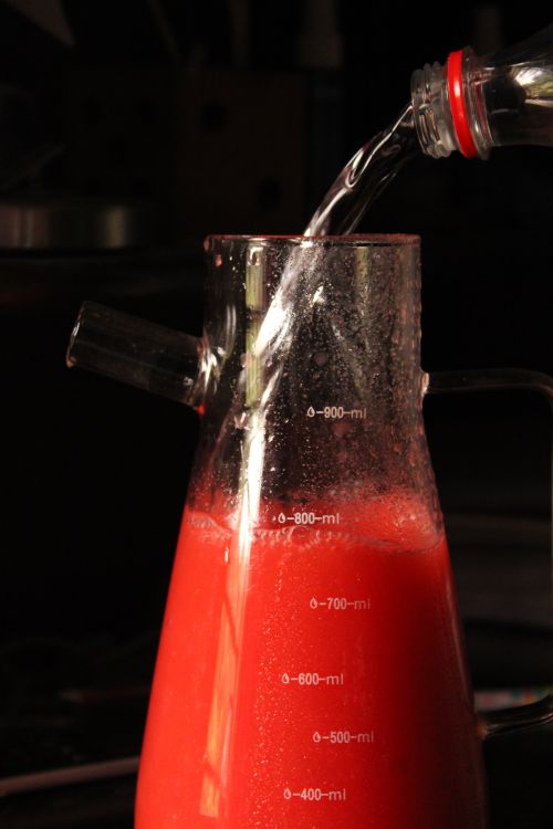 Free Red beverage in a glass measuring jug with water being poured in. Stock Photo