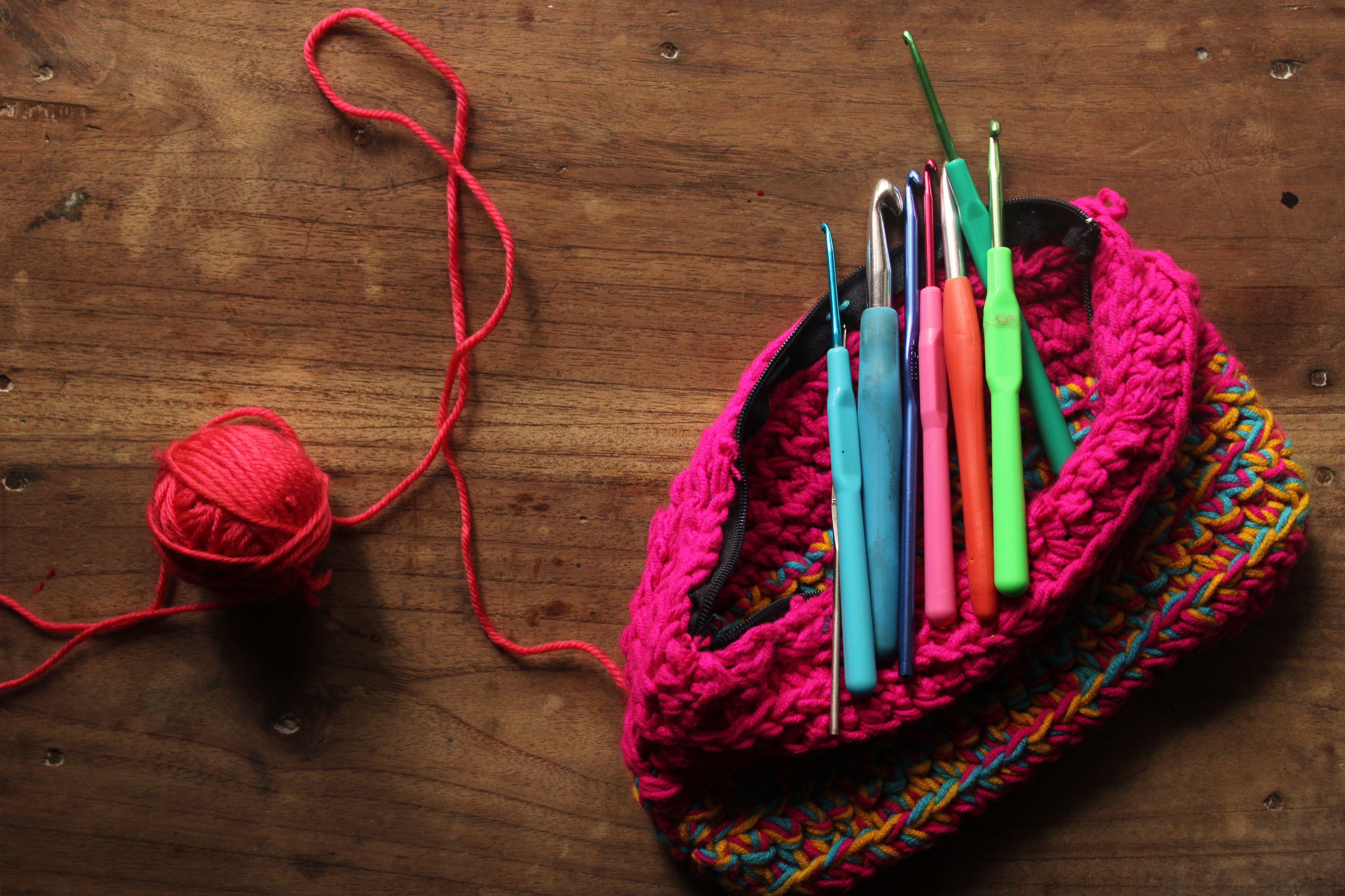 Vibrant crochet hooks and yarn ball on rustic wooden surface, perfect for crafting themes