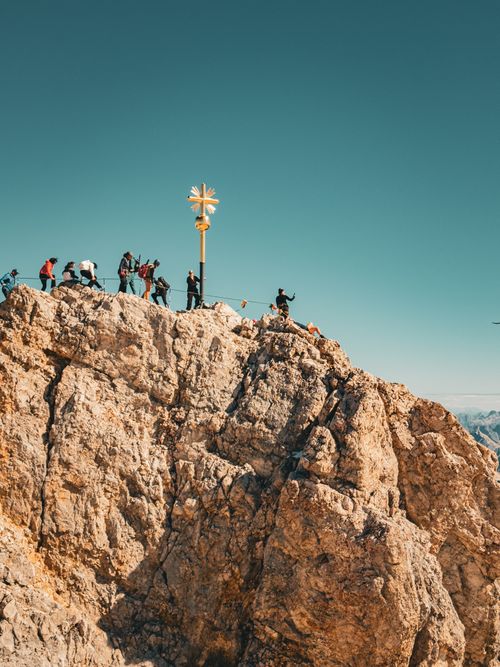 Free Group of hikers reaching the summit of Zugspitze in Germany, marked by a golden cross. Stock Photo