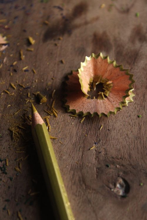 Free Detailed close-up of a sharpened pencil with spiral wood shavings on a wooden desk. Stock Photo