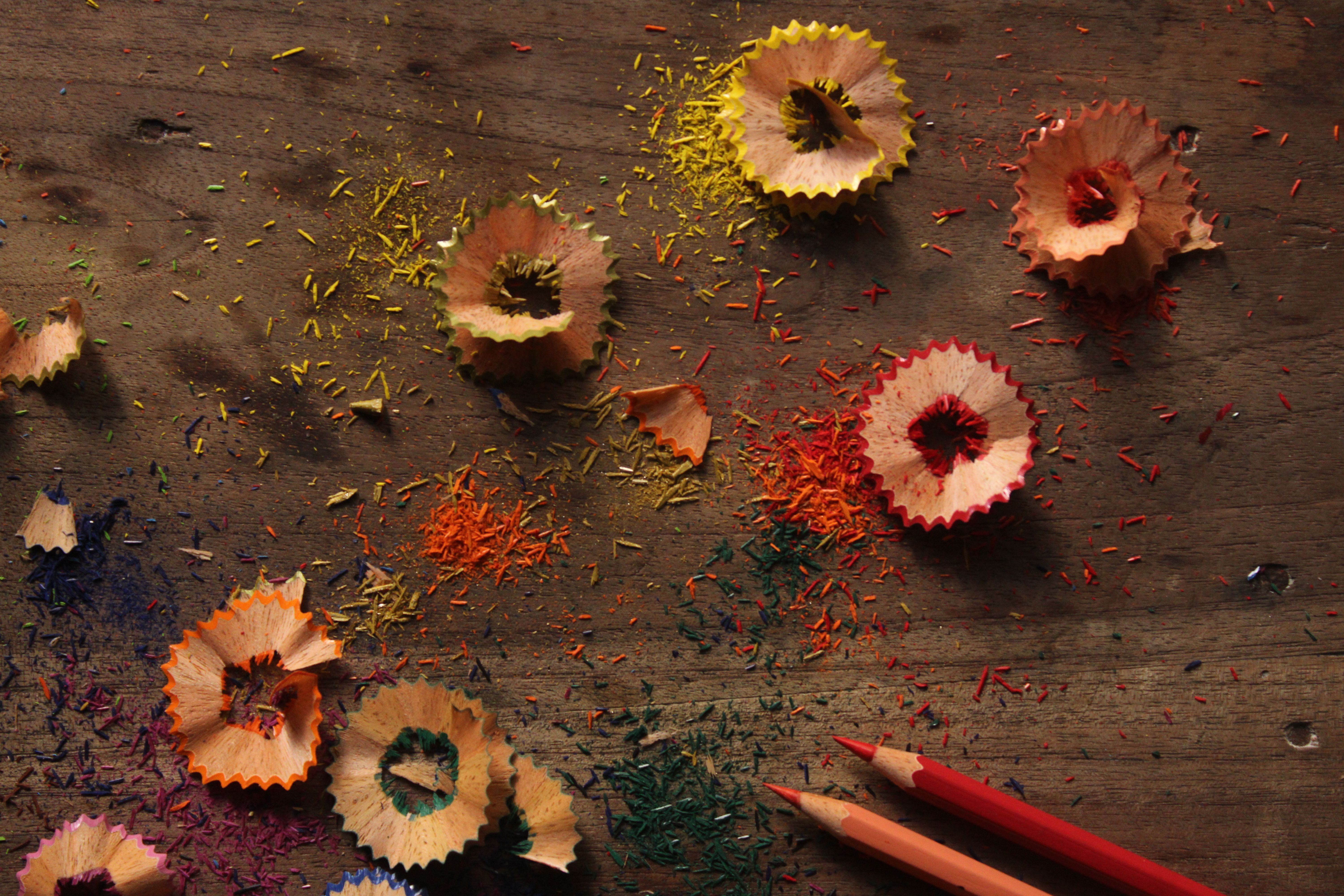 Vibrant pencil shavings and colorful debris on a rustic wooden surface.