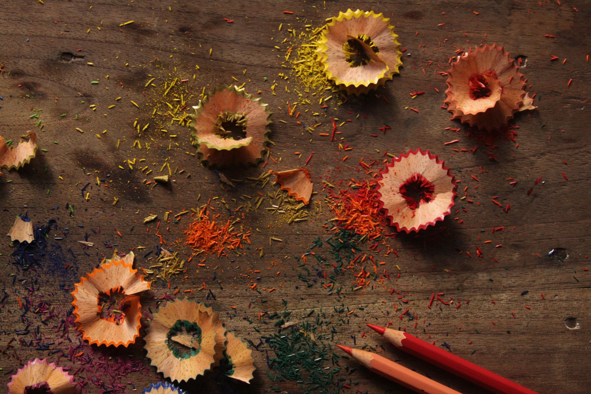 Vibrant pencil shavings and colorful debris on a rustic wooden surface.