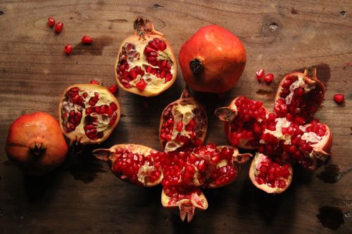 Free Pomegranate halves and seeds displayed on a rustic wooden surface. Stock Photo