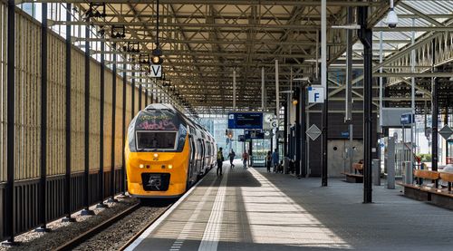 Free Bright yellow train at a European railway station with minimal passengers. Stock Photo