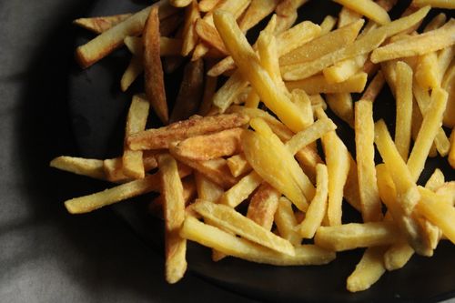 Free Appetizing and crunchy French fries served on a dark plate, perfect for food lovers. Stock Photo