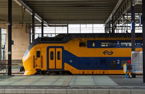 Free Dutch double-decker train stationed at an indoor platform, showcasing vibrant colors. Stock Photo
