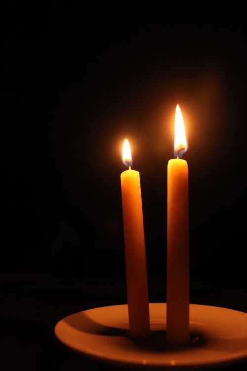 Free Two lit candles on a plate create a cozy and serene ambiance in the dark. Stock Photo