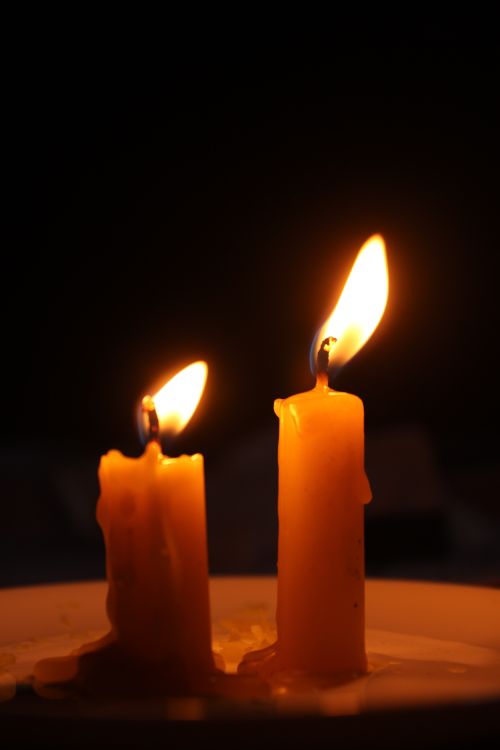 Free Two lit candles casting a warm glow against a dark background, evoking serenity. Stock Photo
