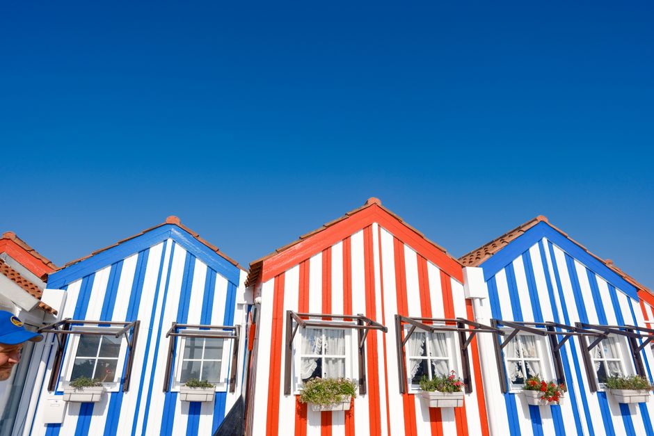 Vibrant red and blue striped houses under a clear blue sky, featuring bright window boxes.