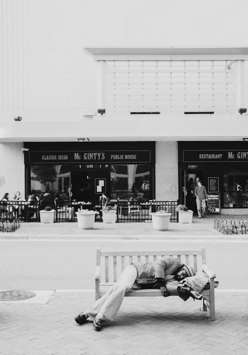 Grayscale Photo Of Man Sleeping On A Bench