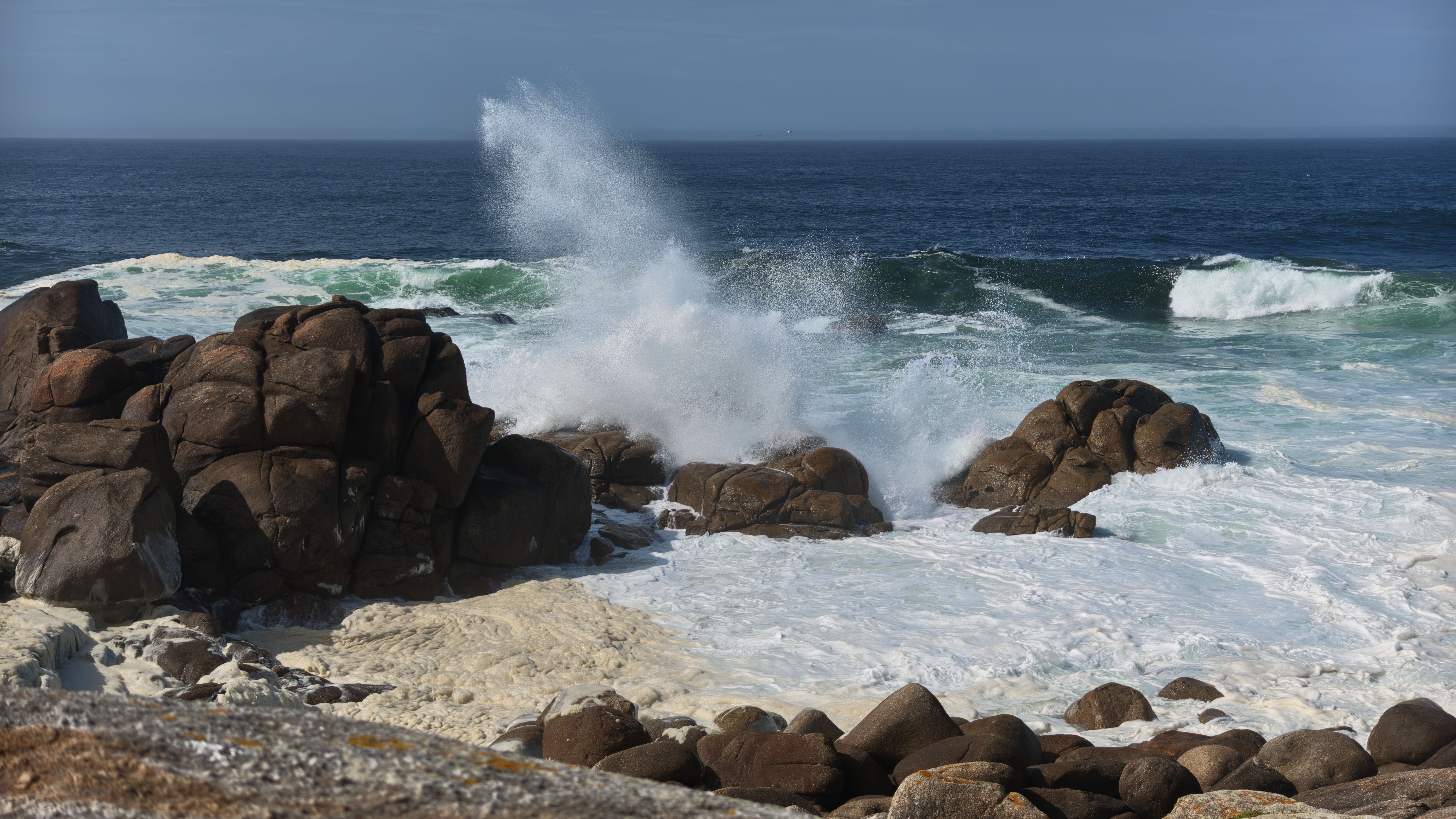 Fotomural Las poderosas olas del océano chocan contra la costa rocosa, creando un paisaje marino espectacular.