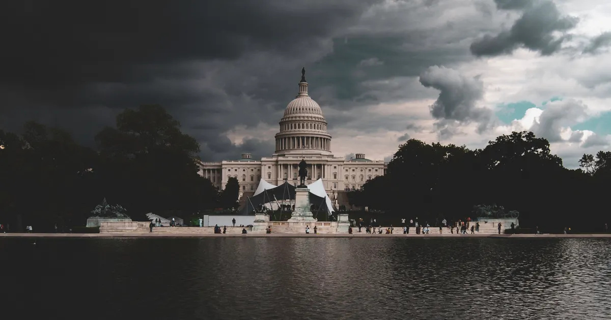 The US Capitol across a reflecting pool under dark clouds, representing compliance requirements and employer obligations