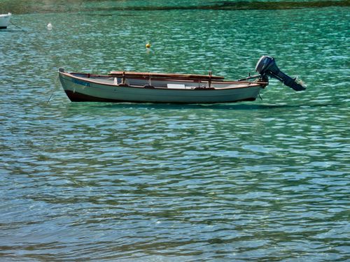 Free A serene view of a small boat resting on clear turquoise water with gentle ripples. Stock Photo