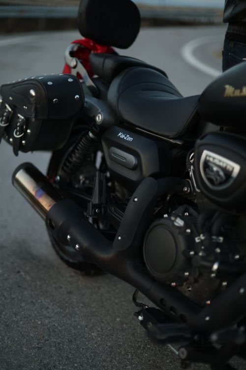 Free Detailed view of a black motorcycle parked on a road with saddle bags. Stock Photo